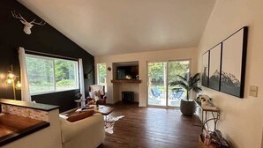 Un vaste espace de vie agrémenté d’une cheminée, d’une grande fenêtre et d’un coin salon confortable.