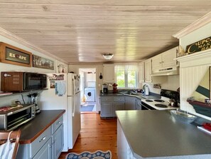 A kitchen with wooden cabinets, a microwave, a stove, and a sink.
