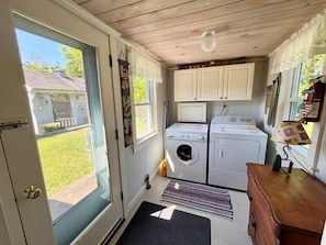 A compact laundry room with two washing machines, a dryer, and a wooden cabinet.