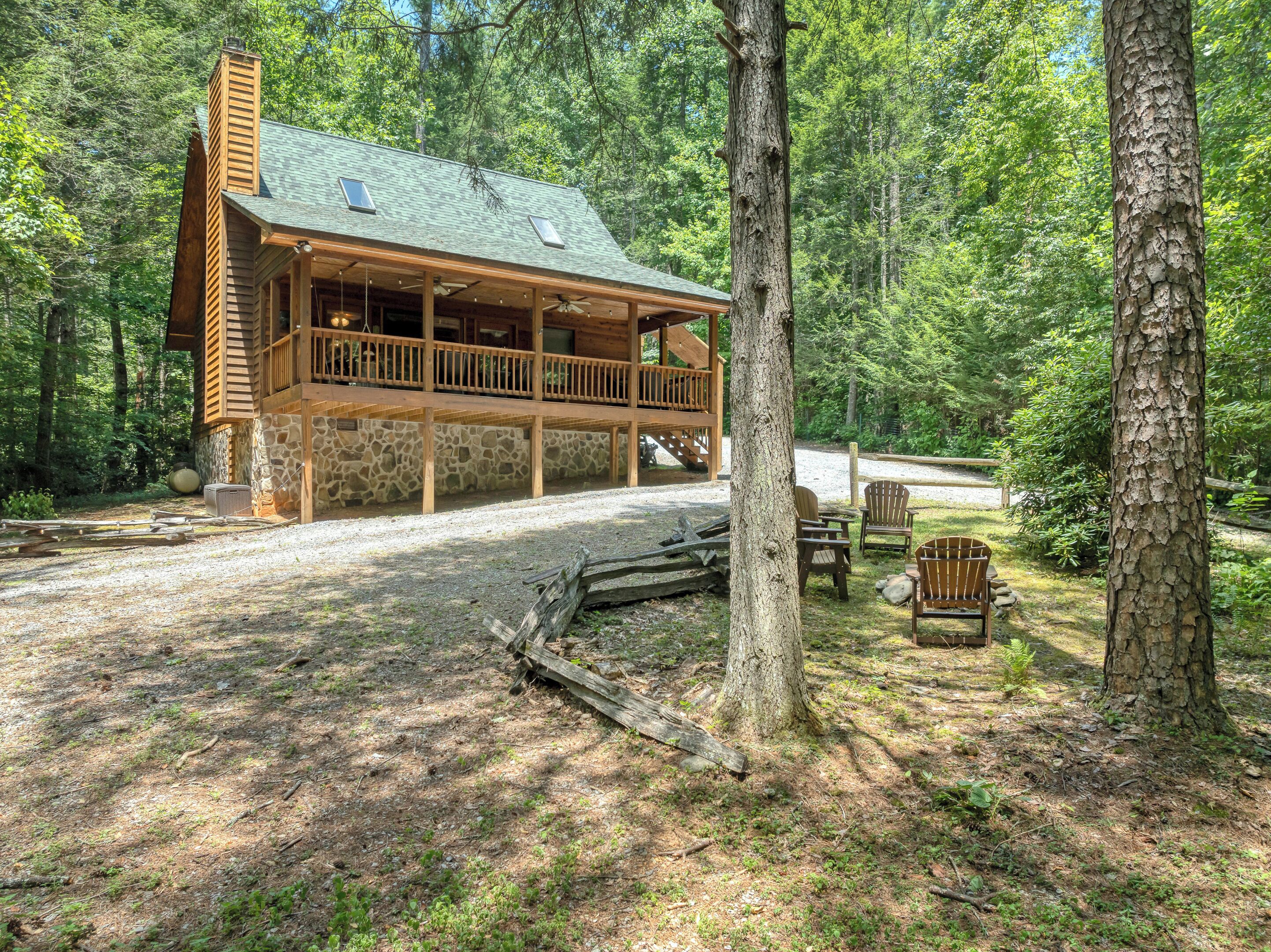 A cabin with a stone foundation, wooden deck, and a covered porch.
