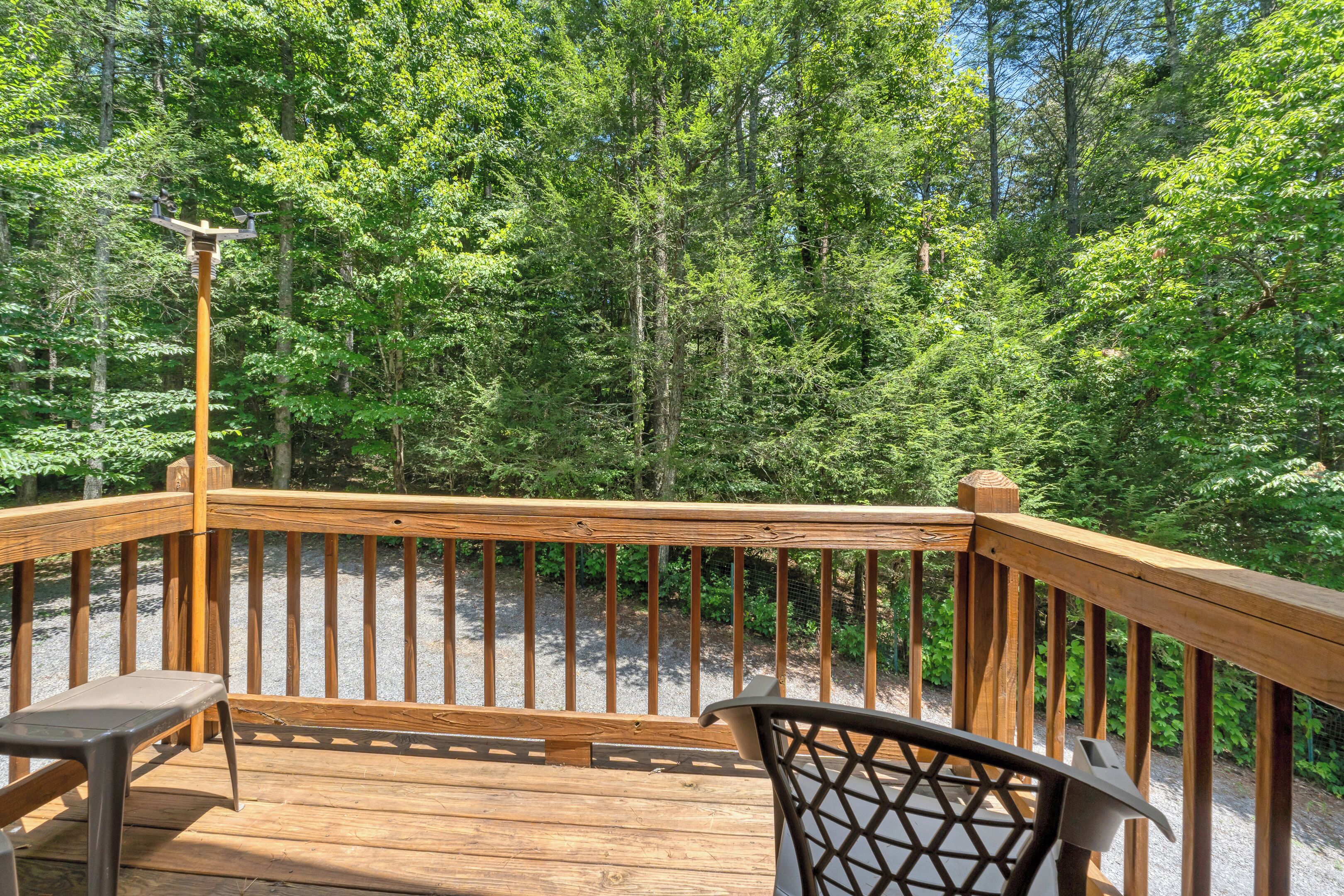 A wooden deck with a railing, a bench, and a chair.