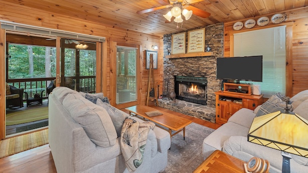 A cozy cabin interior with a stone fireplace, wooden ceiling, and a television on a wooden stand. - SECLUDED♤Bonfire pit♤2 bdrm/2bath♤Pet friendly (Townsend)