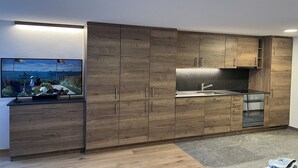 A modern kitchen with wooden cabinets, a built-in oven, and a large window overlooking a scenic view. - Studio with magnificiant view of the Matterhorn (Zermatt)