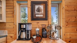 Cozinha de cabana de madeira com cafeteira, liquidificador e utensílios de cozinha na bancada.
