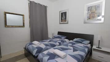 A hotel room with a bed, a nightstand, a lamp, a mirror, and two framed pictures on the wall.