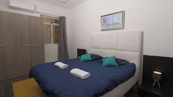 Een slaapkamer met een bed, een kledingkast, een schilderij en een bedlampje.