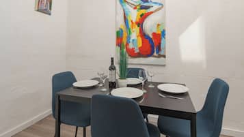 A dining area with a table set for four, chairs, a wine bottle, and a potted plant.