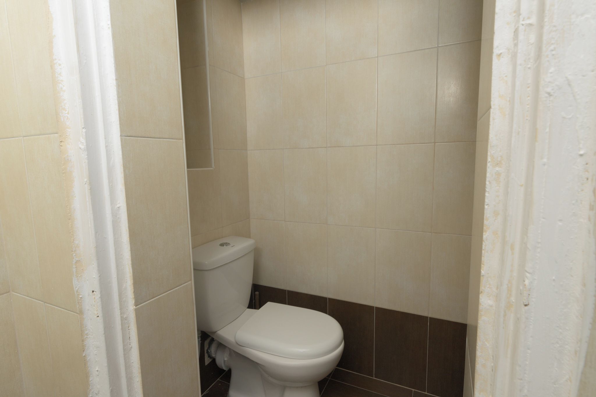 A small, narrow bathroom with a toilet and a wall-mounted sink.