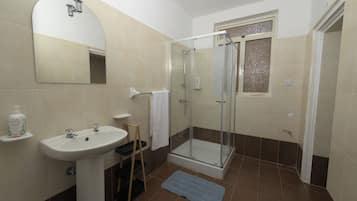 A bathroom with a sink, mirror, shower, and a towel rack.