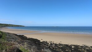A coastal beach with rocky terrain and a clear view of the sea. - Tritons Retreat (Moelfre)