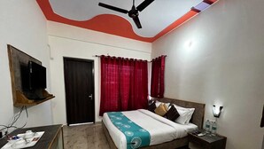 A hotel room with a bed, a desk with a computer, a TV, and a ceiling fan. - Hotel Starwood (Lansdowne)