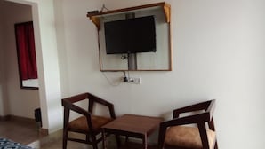 A room with a TV mounted on the wall, two wooden chairs, and a small table. - Hotel Starwood (Lansdowne)