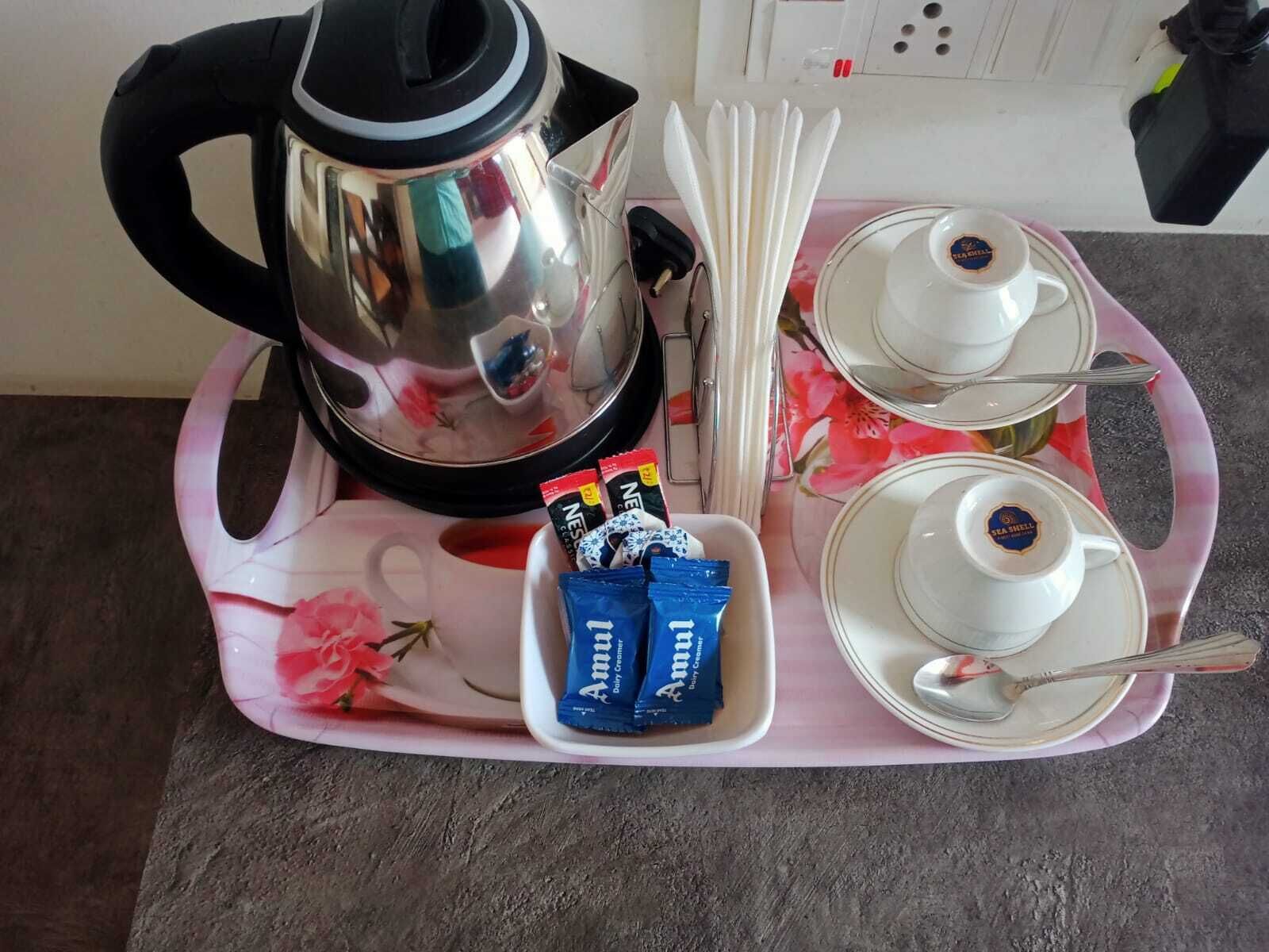 A kitchen setup with a kettle, teapot, cups, and tea bags on a tray.