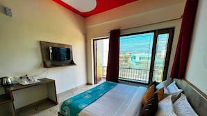 A hotel room with a bed, a TV mounted on the wall, a desk with a kettle and cups, and a window with curtains. - Hotel Starwood (Lansdowne)
