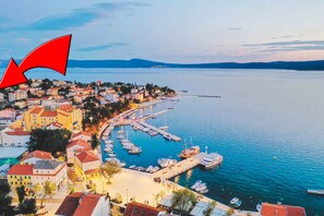 Un pueblo costero con un puerto deportivo, edificios con tejados rojos y una vista despejada del mar.