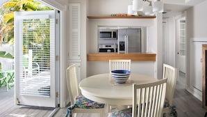 A kitchen with a white table and chairs, a blue and white bowl, and a microwave above the counter. - Shipyard 208-6 Condo in Truman Annex-2 bedroom 2 bath, close to Duval w/ pool (Key West)