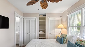 A bedroom with a bed, a TV, a ceiling fan, a window with blinds, and a closet with sliding doors. - Shipyard 208-6 Condo in Truman Annex-2 bedroom 2 bath, close to Duval w/ pool (Key West)