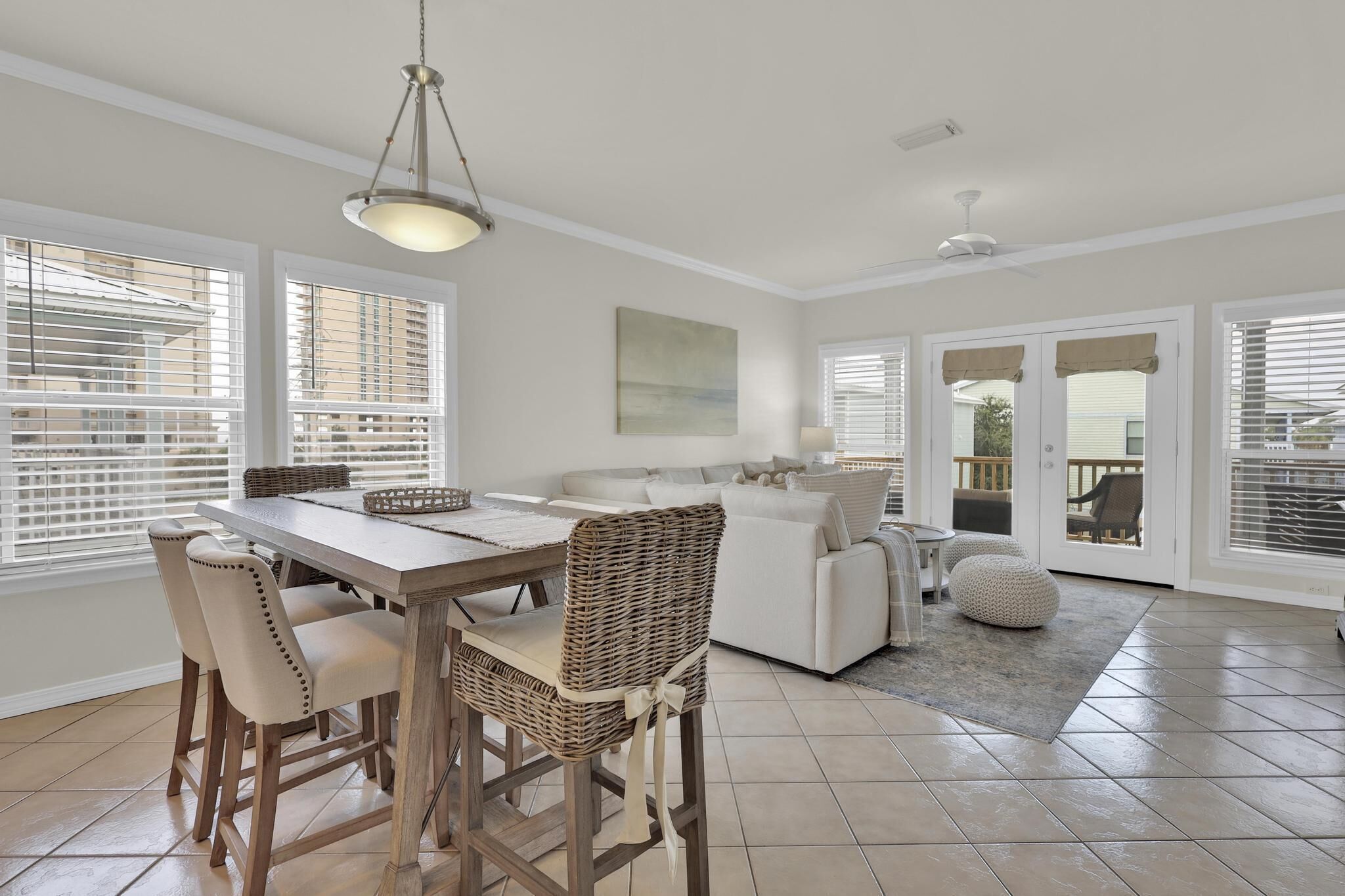 A spacious dining area with a wooden table and chairs, a wicker chair, and a hanging light fixture.