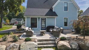 A house with a porch, outdoor seating, and a grill.