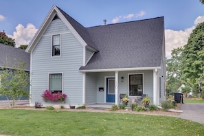 A light blue two-story house with a dark gray roof, a front porch, and a mailbox labeled "MAL".