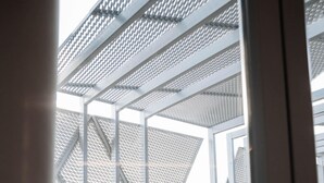 A modern architectural structure with a metal framework and patterned facade, viewed from an interior space with a wooden floor and a metal railing. - Hotel Carpe Diem Mostar (Mostar)