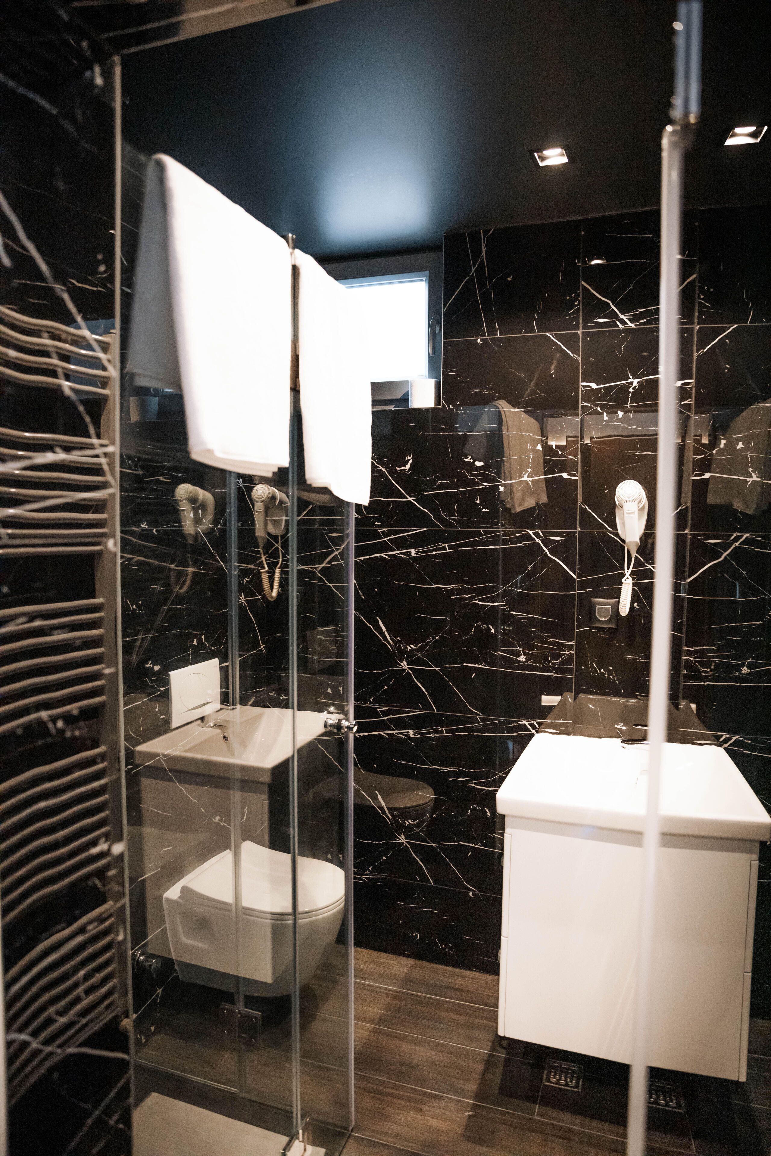 Een moderne badkamer met een glazen douchecabine, een witte wastafel en een toilet.