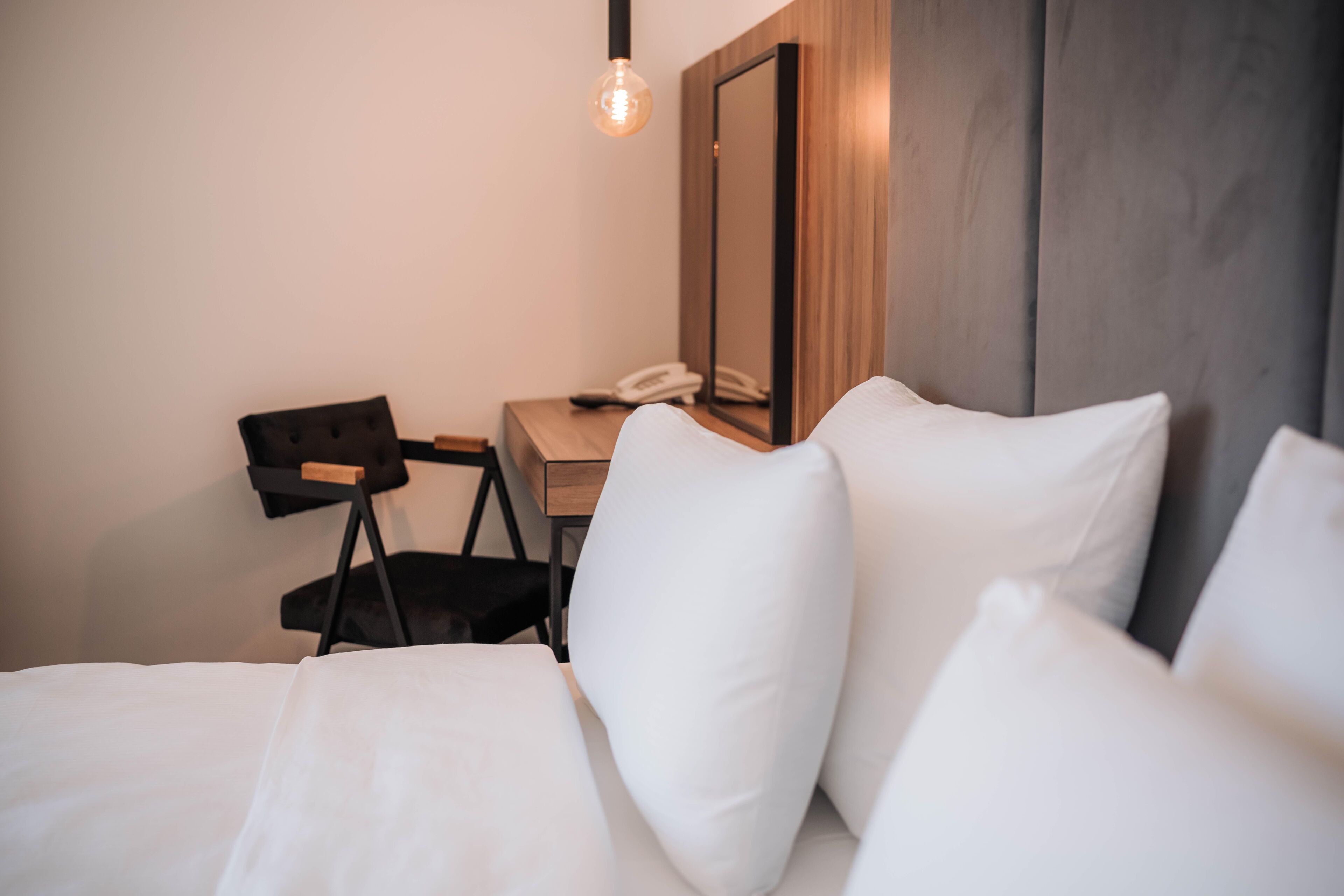 Ein Hotelzimmer mit Bett, Schreibtisch, Stuhl und Telefon.