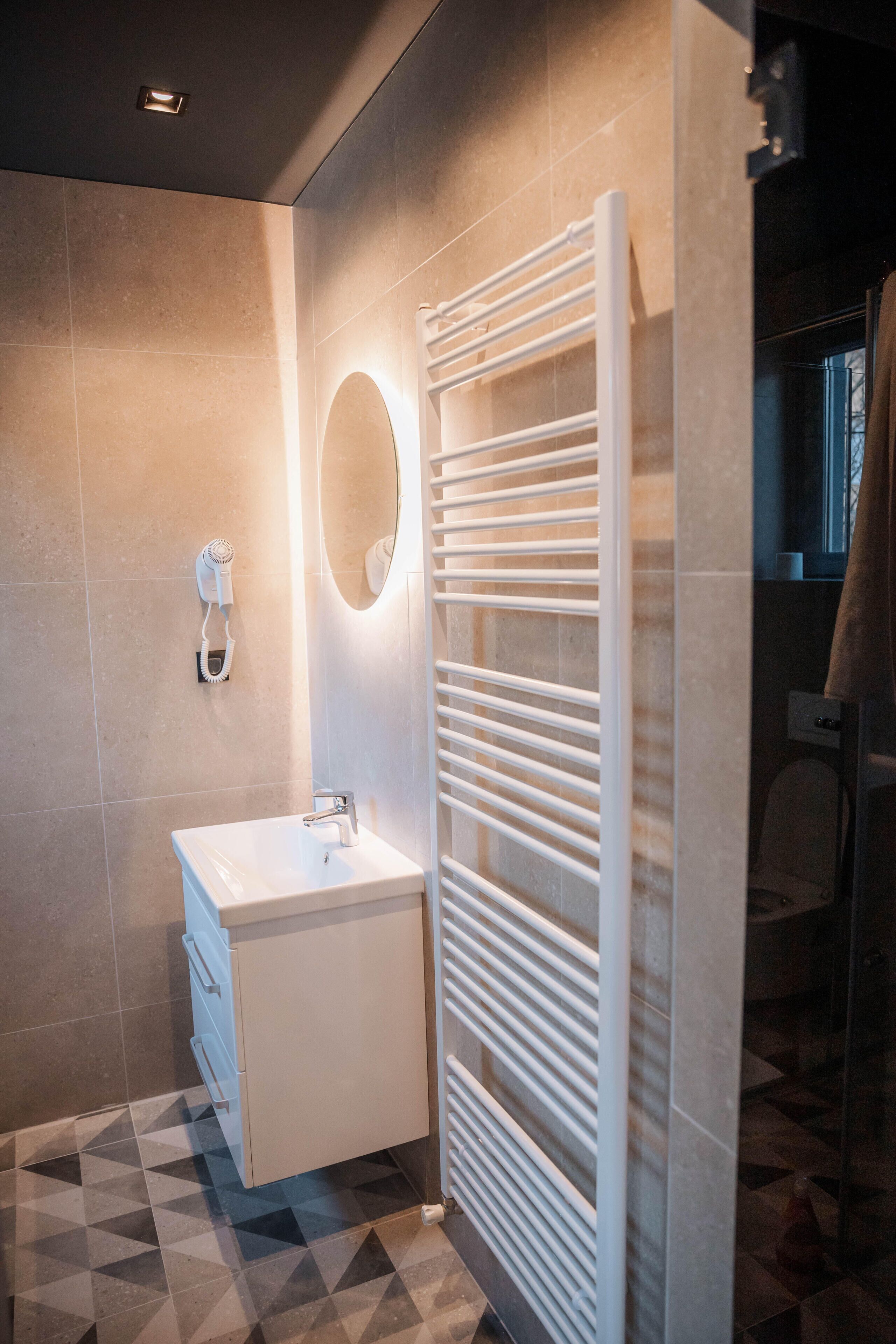 A modern bathroom with a white sink, a towel rack, and a mirror.
