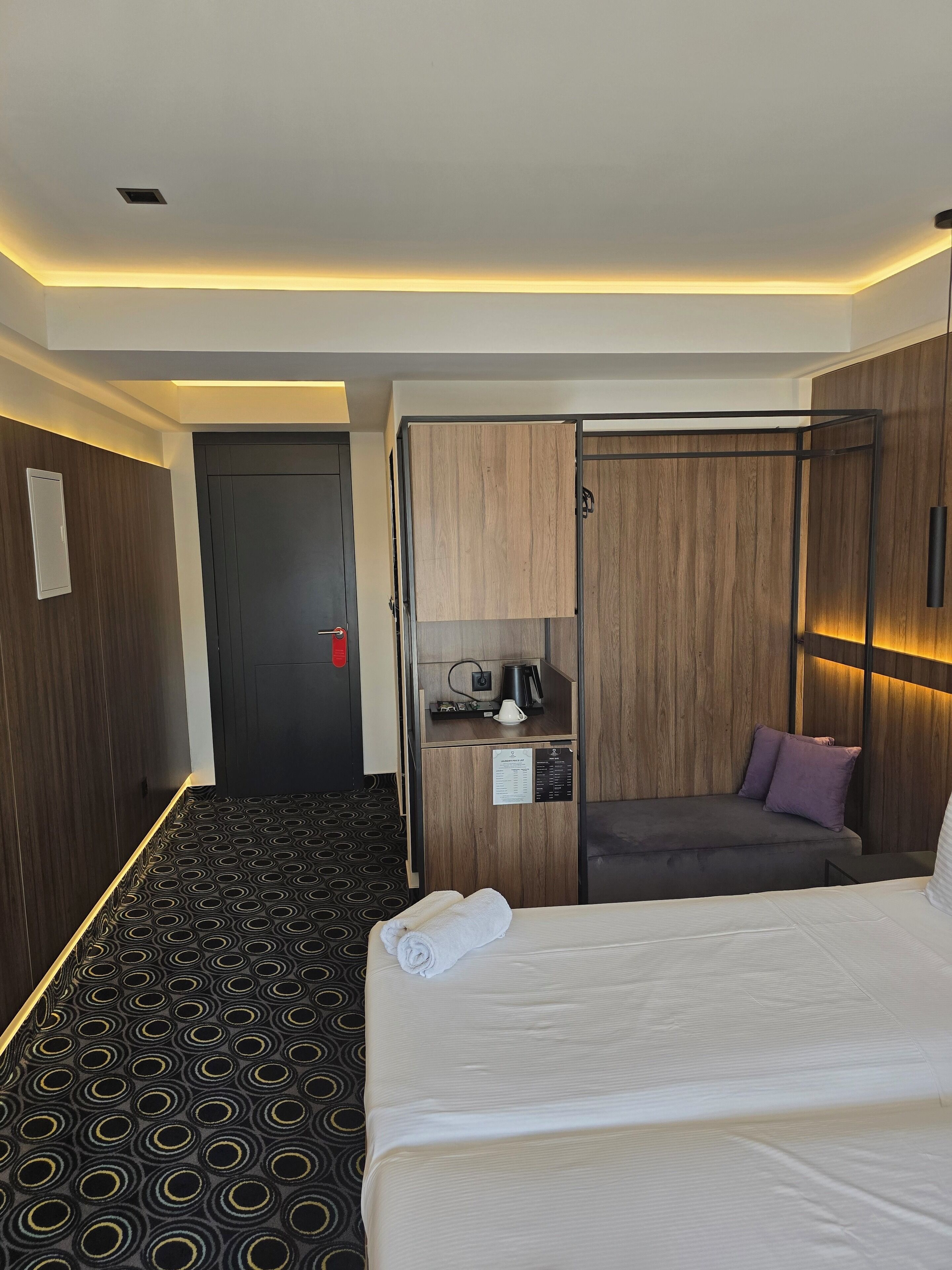 Une chambre d’hôtel comprenant un lit, un coin salon avec un canapé, une petite table avec une machine à café et une armoire.