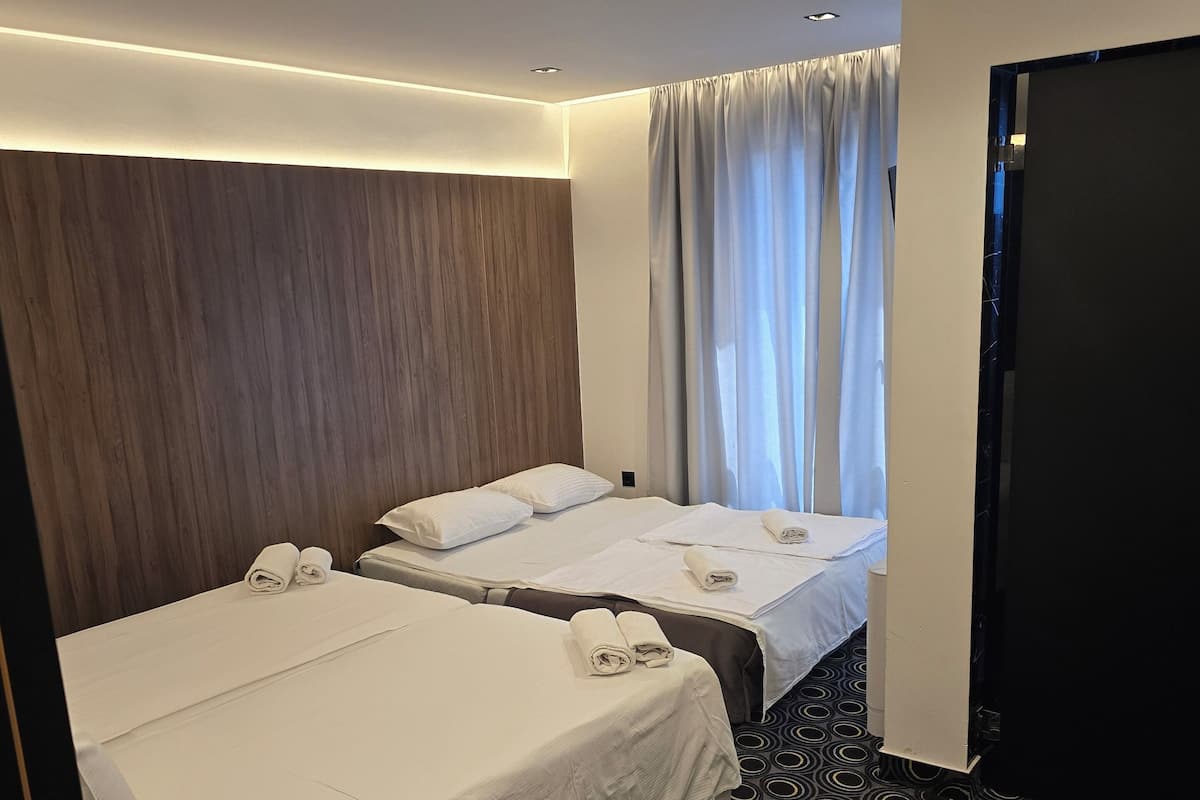 A hotel room with two beds, a dark patterned carpet, and a wooden headboard.