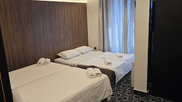 A hotel room with two beds, a dark patterned carpet, and a wooden headboard.