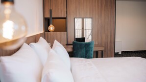 A hotel room with a large bed, a desk with a chair, a mirror, and a hanging light fixture. - Hotel Carpe Diem Mostar (Mostar)