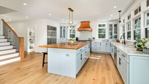 Una cocina moderna con una isla central, muebles blancos y suelo de madera.