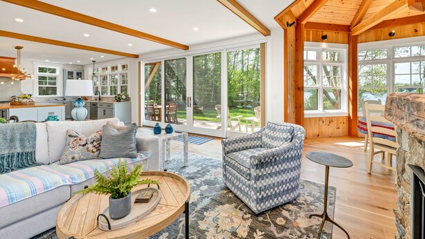 Un espacio habitable amplio con sofá, sillón y mesa de centro, ventanas grandes y vistas al exterior.