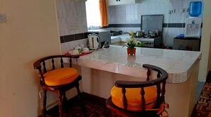 Functional kitchen with central island, stove, kettle, sink, and seating area.