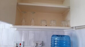 Kitchen area with a white tiled backsplash and a shelf for storing essentials.