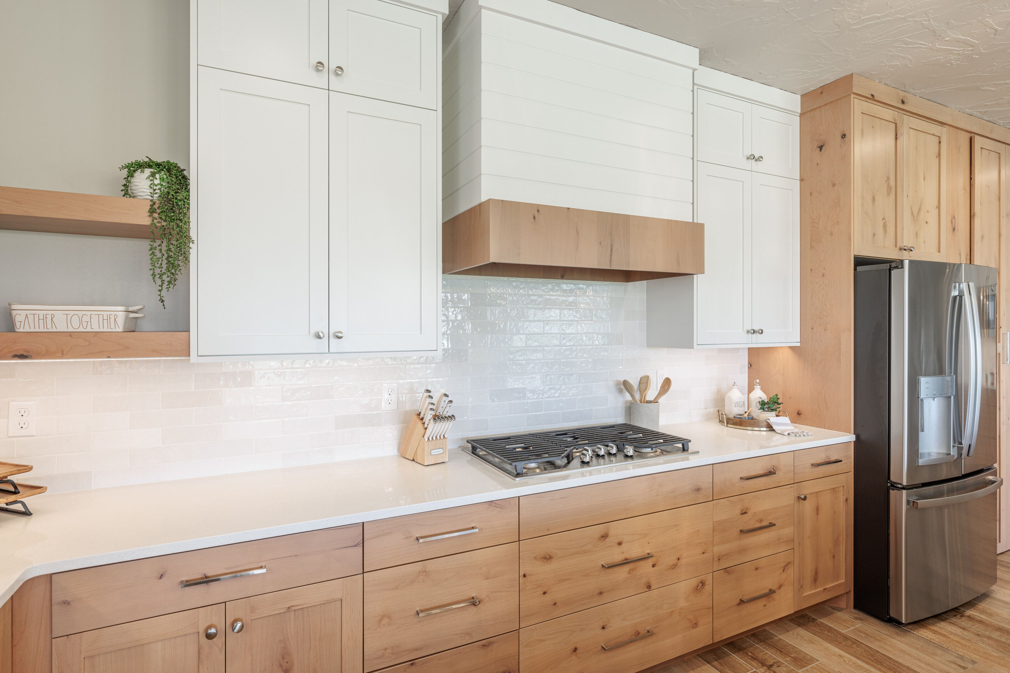A modern kitchen with white cabinetry, a stainless steel refrigerator, and a built-in gas stove.
