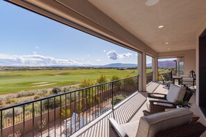 A balcony with a view of a golf course, outdoor furniture, and a patio area. - Large 5BR Luxury Home w/Private Heated Pool & Spa (St. George)