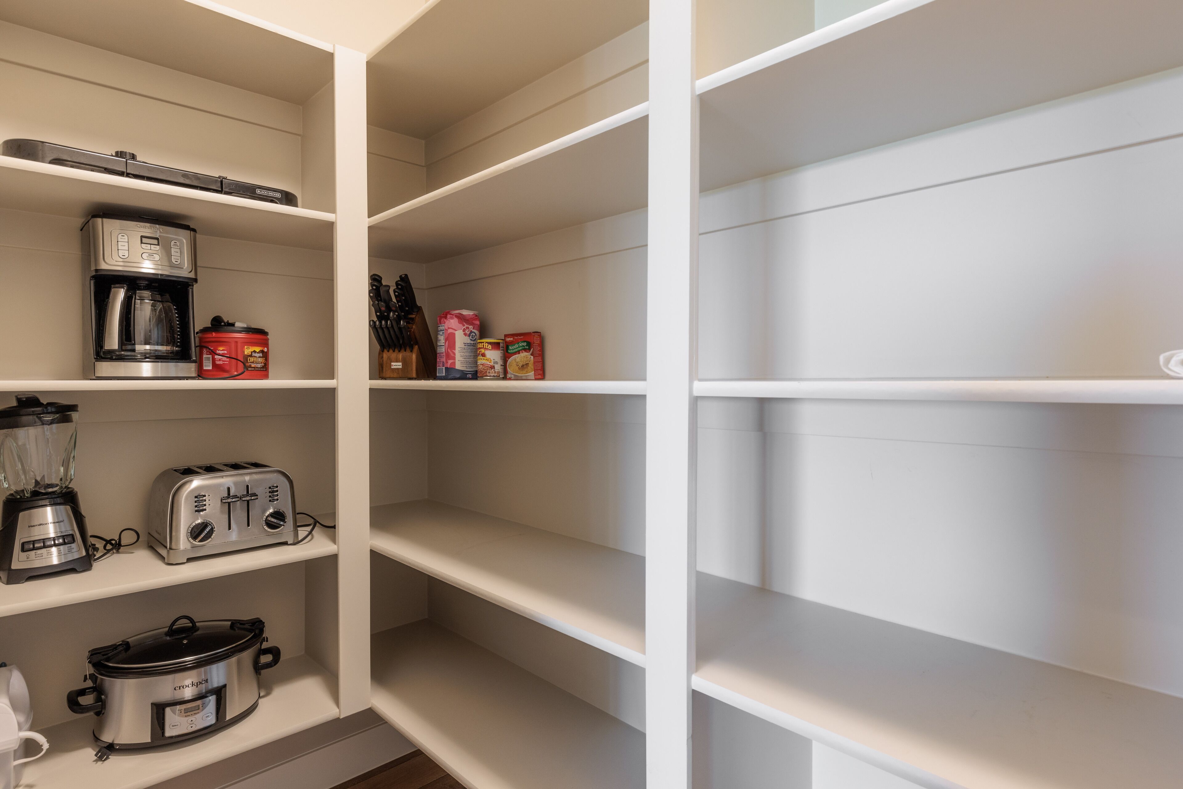 Una cocina con cafetera, tostadora y olla de cocción lenta en los estantes.