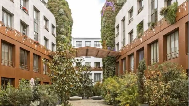 Ein Innenhof mit einem zentralen Weg, umgeben von Gebäuden mit Balkonen und vertikalen Gärten.