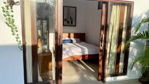 Un dormitorio con una cama, una mesita de noche y un ventanal con cortinas.