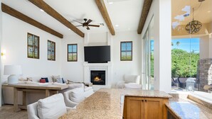 A spacious living area with a fireplace, a large TV, and a kitchen with granite countertops. - HAC01 - Haciendas at La Quinta (La Quinta)