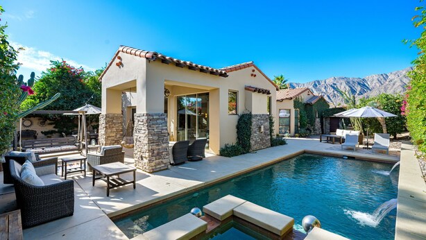 A poolside area with outdoor furniture, a stone wall, and a mountain backdrop. - HAC01 - Haciendas at La Quinta (La Quinta)