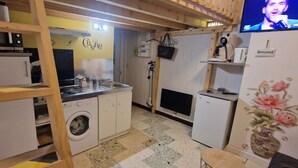 Een praktische keuken met een wasmachine, een magnetron en een kleine koelkast.