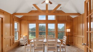 A dining area with a wooden table and chairs, large windows, and a ceiling fan. - New - Pool,Game Room,Access 2 Beach,Golf Community (Corolla)