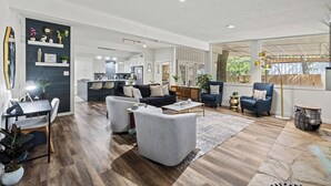 Una sala de estar moderna con un sofá, sillones, una mesa de centro y un escritorio con una computadora.