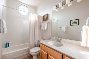A bathroom with a bathtub, toilet, sink, and a large mirror.