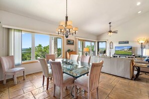 A spacious dining area with a glass table, cushioned chairs, and a view of the outdoors.