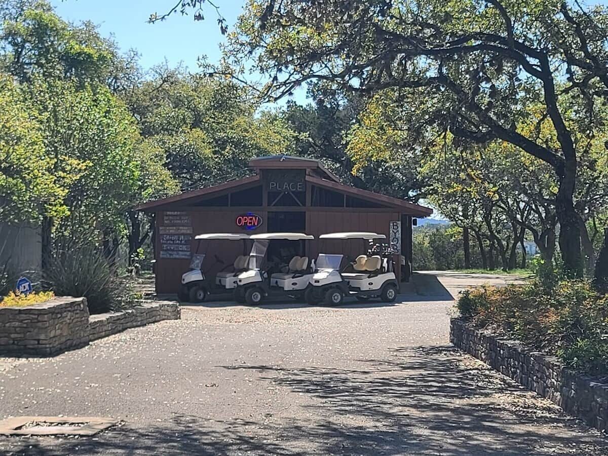 A building labeled 'PLACE' with a sign indicating it's open. There are three golf carts parked in front.