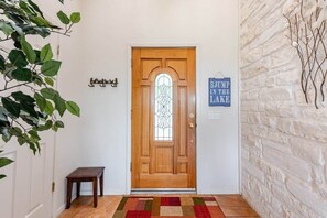 A wooden door with a glass panel, a bench, a rug, and a wall-mounted sign.